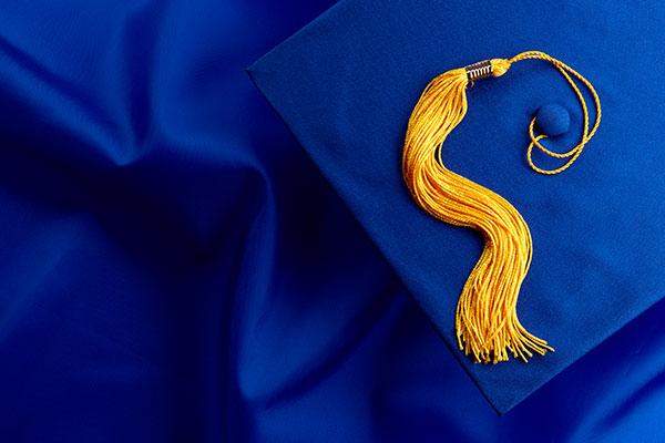 蓝色毕业礼服上的蓝色学位帽和黄色流苏